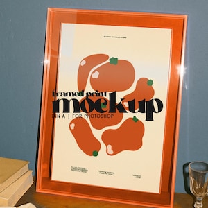 Może przedstawiać: Pomarańczowa makieta druku w ramie z abstrakcyjnym wzorem pomarańczowych kształtów z zielonymi akcentami. Tekst "framed print mockup" jest czarny, z dodatkowym tekstem poniżej. Rama ma jasnopomarańczowy kolor.