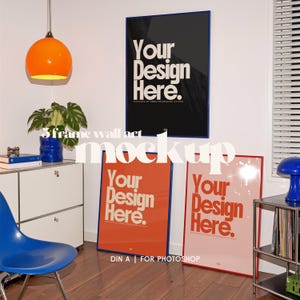 May include: Three framed wall art mockups with the text "Your Design Here". The frames are in black, orange, and pink, with blue and red borders. The image also includes a blue chair, a plant, and an orange pendant light. The text "DIN A | FOR PHOTOSHOP" is also visible.