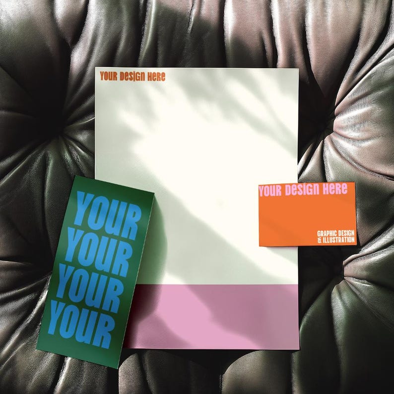 May include: A mock-up of a business card and letterhead design. The letterhead is white with a pink stripe at the bottom. The business card is orange with the text "Your design here" in pink. The text on the letterhead says "Your design here".