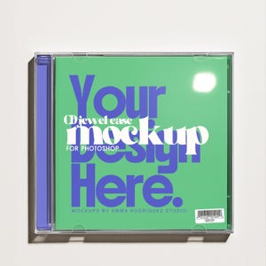 Może przedstawiać: Makieta etui na płytę CD z zielonym tłem i tekstem "Your Design Here" w kolorze niebieskim i białym. Etui ma przezroczysty plastikowy przód i fioletowy grzbiet. Widoczny jest również tekst "CD jewel case mockup for Photoshop".