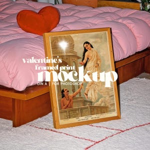 May include: A framed print mockup featuring a vintage illustration of a woman in a white sari and a man. The frame is light brown, and the print is propped on a white rug with a red pattern. The text "valentine's framed print mockup" is visible.