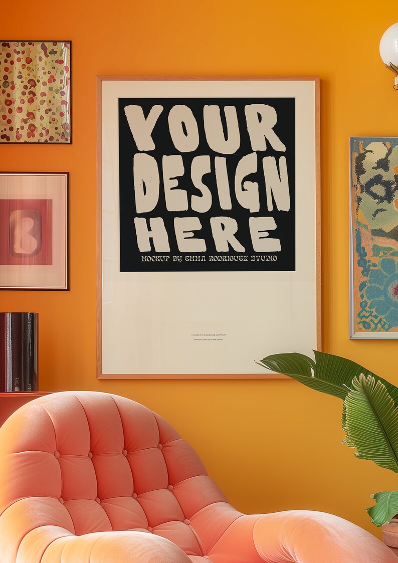 May include: A framed poster with a black background and white text that reads "YOUR DESIGN HERE" with the words "MOCKUP BY EMMA RODRIGUEZ STUDIO" below. The poster is hanging on a yellow wall with a pink armchair in the foreground.