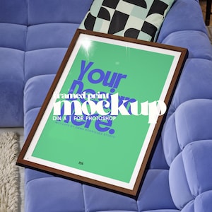 Può includere: Un mockup di stampa incorniciata con sfondo verde e testo bianco che recita "Your framed print mockup". La cornice è marrone e la stampa è su un divano blu. È visibile anche il testo "DIN A FOR PHOTOSHOP".