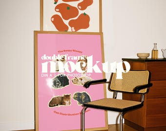 May include: A framed pink poster with cat images and text, "The Eeepy Bleepy doubleframe mock up". Above it, a framed abstract art print with orange shapes. A mid-century modern chair with a woven seat and back is in the foreground.