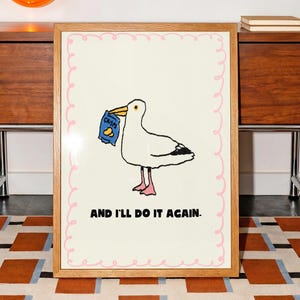 Op de afbeelding: Een ingelijste print met een cartoon zeemeeuw die een zak chips vasthoudt. De zeemeeuw is wit met zwarte vleugelmarkeringen en roze poten. De tekst "AND I'LL DO IT AGAIN." staat onder de afbeelding.