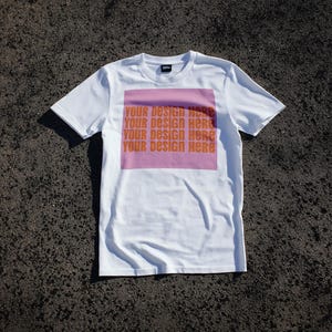 May include: White t-shirt with a pink square print that says "Your design here" four times.