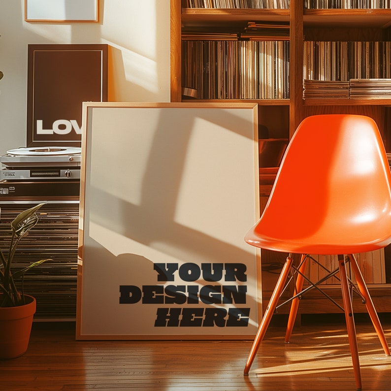 以下が含まれることがあります： 「YOUR DESIGN HERE」という黒い文字が書かれた、大きな白い額縁付きのポスター。ポスターはレコードでいっぱいの木製の書棚に立てかけられている。ポスターの前に明るいオレンジ色の椅子が置かれている。