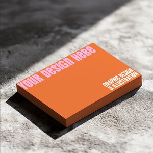 May include: Orange business card mockup with the text "YOUR DESIGN HERE" in pink letters and the text "GRAPHIC DESIGN & ILLUSTRATION" in white letters.