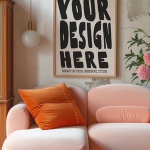 May include: A pink velvet sofa with an orange velvet pillow and a framed poster that says "YOUR DESIGN HERE" with the text "MOCKUP BY EMILI RODRIGUEZ STUDIO" below it.