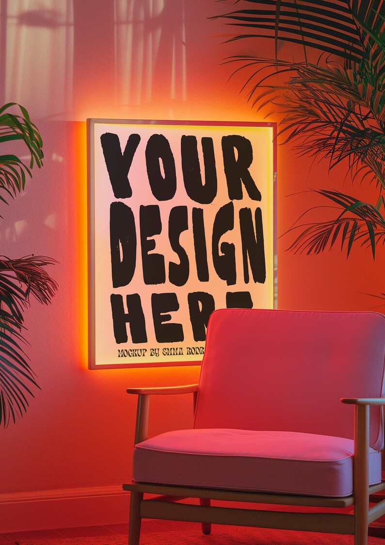 May include: A pink armchair with wooden legs sits in front of a white framed light box with the text "YOUR DESIGN HERE" in black. The light box is illuminated with a warm orange glow. The wall behind the chair is a light pink color.