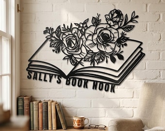 May include: A black metal wall art piece shaped like an open book with a bouquet of roses and leaves emerging from the pages. The text SALLY'S BOOK NOOK is cut out in bold capital letters along the bottom edge of the open book design.