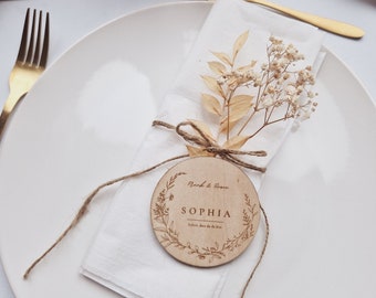 May include: A white plate with a white napkin, a gold spoon, and a wooden place card with the name "Sophia" written on it. The place card is decorated with a floral design and the text "Thank & Rose" and "Schön, dass du da bist".