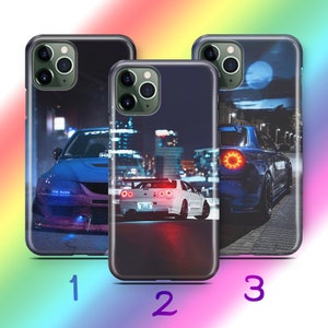 Op de afbeelding: Drie verschillende telefoonhoesjes met een nachtelijke stadsscène en een auto op de voorgrond. De eerste hoes heeft een blauwe auto met de tekst "ITS HUGE" aan de zijkant. De tweede hoes heeft een witte auto met de tekst "NISSAN" aan de achterkant. De derde hoes heeft een blauwe auto met rode achterlichten.