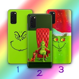 Puede incluir: Tres fundas para teléfono con diseños del Grinch. Las fundas presentan la cara del Grinch, el Grinch sentado en un trono rojo con su perro y el Grinch con un gorro de Papá Noel. Las fundas son verdes y rojas.