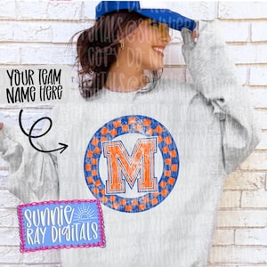 May include: A light gray sweatshirt with a distressed orange and blue letter "M" design. The letter is inside a checkered circle. The text "YOUR TEAM NAME HERE" is above the sweatshirt design. The text "SUNNIE RAY DIGITALS" is in a pink and blue box.
