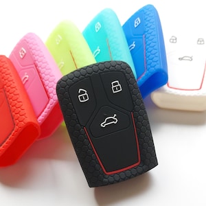May include: A set of 10 silicone key covers in various colors, including red, pink, light blue, green, blue, and white. The covers are designed to fit a car key fob with four buttons and a car icon. The covers have a textured pattern and a red accent around the edges.