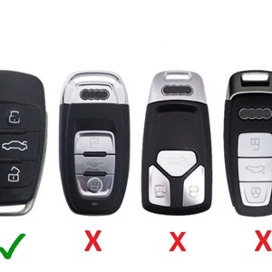 May include: Black car key with silver buttons and a key fob. The key has a button for locking, unlocking, and opening the trunk. The key is for a car.