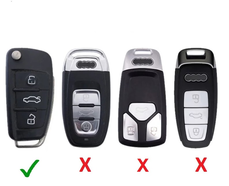 May include: Black car key with silver buttons and a key fob. The key has a button for locking, unlocking, and opening the trunk. The key is for a car.