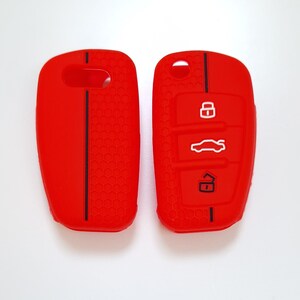 May include: Two bright red car key fobs. One has a solid surface with a black stripe, the other has three white icons: a lock, a car, and an unlock symbol. Both have a honeycomb texture.