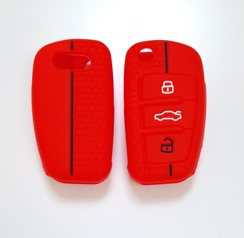 May include: Two bright red car key fobs. One has a solid surface with a black stripe, the other has three white icons: a lock, a car, and an unlock symbol. Both have a honeycomb texture.