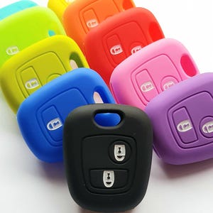 May include: Assortment of colourful silicone key covers for car keys. The covers are in various colours, including blue, green, yellow, orange, red, pink, and purple. The covers have two buttons and a key ring.
