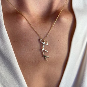 Può includere: Una collana color oro con il nome "Julide" scritto in corsivo. Il ciondolo è appeso a una catena delicata. La collana è mostrata su uno sfondo bianco.