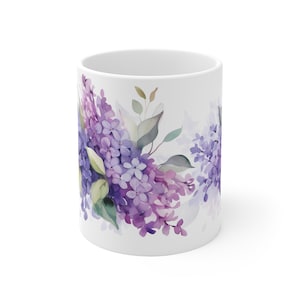 May include: White ceramic mug with a watercolor design of purple and pink lilac flowers and green leaves.
