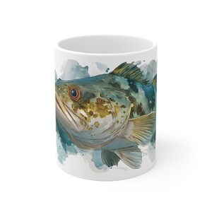 May include: White ceramic mug featuring a watercolor illustration of a fish. The fish has a detailed design with shades of blue, green, and yellow. The mug is a standard size and shape, suitable for hot or cold beverages.