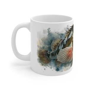 May include: White ceramic mug featuring a watercolor illustration of a fish. The fish has a detailed design with shades of brown, blue, and red. The mug has a curved handle and is suitable for hot or cold beverages.