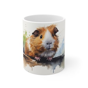May include: A white ceramic mug with a watercolor illustration of a brown and white guinea pig. The guinea pig is looking at the viewer and has a pink nose. The background is a light blue and green watercolor wash.