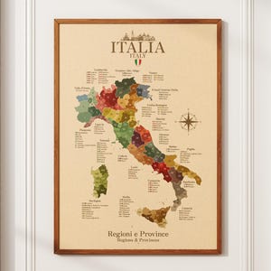 May include: A framed wall map of Italy featuring a beige background with the text ITALIA ITALY at the top and Regioni e Province Regions & Provinces at the bottom. The map displays various Italian regions in muted earth tones with labels.