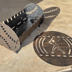 May include: A metal fire pit shaped like a baseball with a baseball player silhouette on a separate metal disc. The fire pit has a textured surface and is designed to hold a fire.