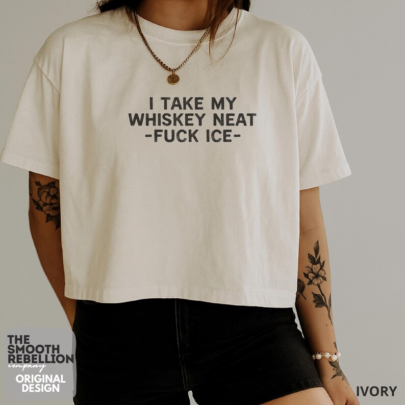 Ivory Comfort Colors boxy tee. The shirt has bold black text reading “I TAKE MY WHISKEY NEAT – FUCK ICE –.” Slightly Cropped. Boxy, relaxed fit. 100% Cotton. Heavy Fabric. Protest & Anti Ice Apparel.