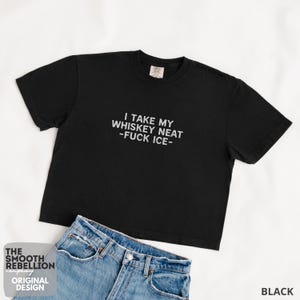 Black Comfort Colors boxy tee. The shirt has bold white text reading “I TAKE MY WHISKEY NEAT – FUCK ICE –.” Slightly Cropped. Boxy, relaxed fit. 100% Cotton. Heavy Fabric. Protest & Anti Ice Apparel.