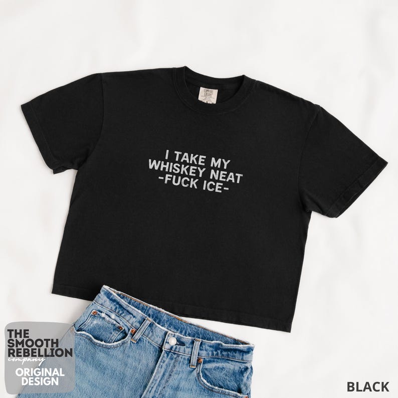 Black Comfort Colors boxy tee. The shirt has bold white text reading “I TAKE MY WHISKEY NEAT – FUCK ICE –.” Slightly Cropped. Boxy, relaxed fit. 100% Cotton. Heavy Fabric. Protest & Anti Ice Apparel.