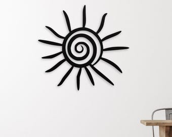 May include: Black sunburst wall art with a spiral centre and radiating lines. The decorative piece is mounted on a white wall above a wooden floor. The sunburst design adds a touch of bohemian style.