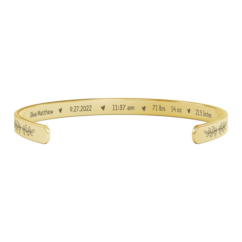 May include: Gold bangle bracelet with engraved text: "Olivia Matthew &hearts; 9.27.2022 &hearts; 11:37 am &hearts; 7 lbs 14 oz &hearts; 21.5 Inches".