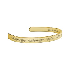 May include: Gold bangle bracelet with an engraved floral design and the name "Olivia Matthew" on the inside.