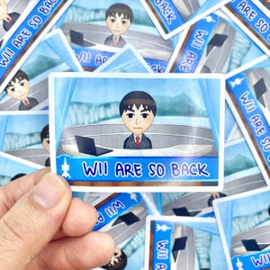 May include: A sticker with a cartoon character in a suit and tie behind a desk with a laptop. The sticker has the text "WII ARE SO BACK" in blue. Other stickers are visible in the background.