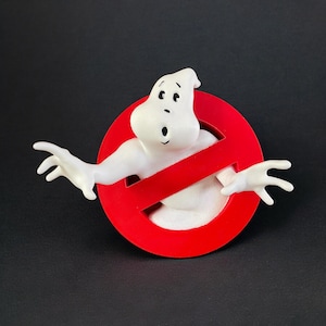 Può includere: Una figura di fantasma bianco dei cartoni animati con le braccia tese che emerge da un cerchio rosso con una barra rossa. La figura ha un'espressione sorpresa con occhi e bocca neri. Lo sfondo è nero.