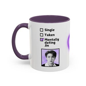 May include: White ceramic mug with a purple interior and handle. The mug features the text "Single", "Taken", and "Mentally dating Jin" with a checkmark next to the last option. A black and white photo of a person is below the text.