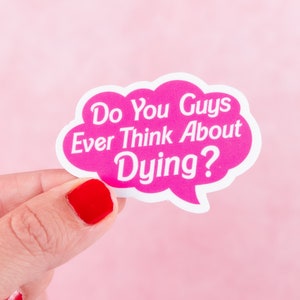 May include: A pink sticker in the shape of a speech bubble with the text "Do You Guys Ever Think About Dying?" in white. The sticker is held by a hand with red nail polish against a pink background.