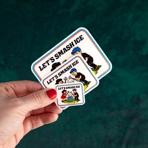 May include: A hand holds three stickers with a retro comic book style. Each sticker features the text "LET'S SMASH ICE" and illustrations of children breaking ice. The stickers have a white background with a blue and red border.