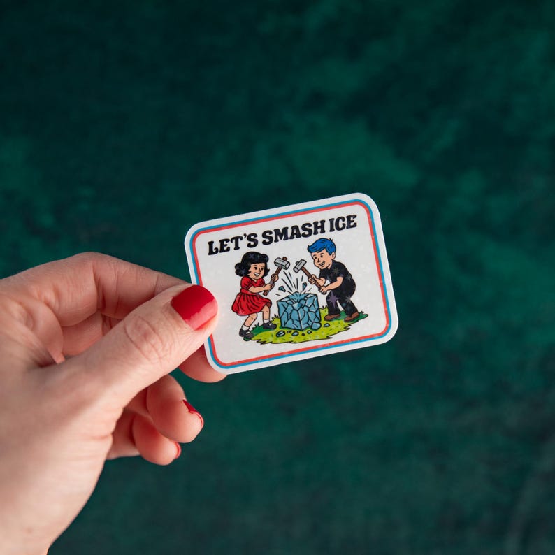 May include: A rectangular sticker with a white background and a blue and red border. The sticker features a cartoon illustration of a girl and boy smashing a blue ice cube with hammers. The text "LET'S SMASH ICE" is at the top.