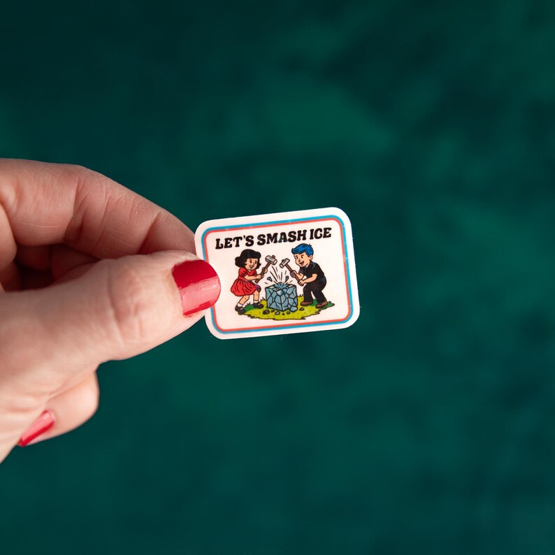 May include: A rectangular sticker with a white border and the text "LET'S SMASH ICE." The sticker features a cartoon illustration of a girl and a boy smashing a blue ice cube with hammers. The background is a teal green.