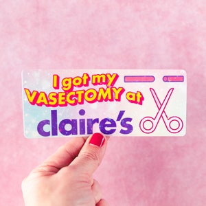 May include: A white sticker with a pink, yellow, and purple design. The sticker says "I got my VASECTOMY at claire's" with a pair of scissors in the corner.
