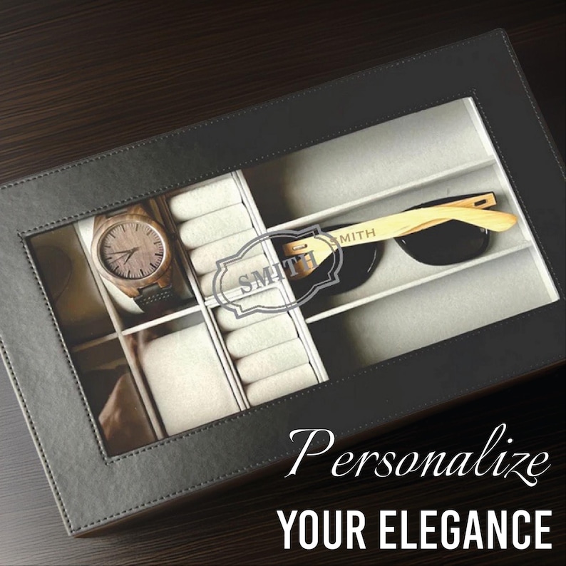 May include: A black leather box with a glass top, showing compartments for storing watches, sunglasses, and jewelry. The box is personalized with the name "SMITH". The text "Personalize Your Elegance" is printed on the front of the box.