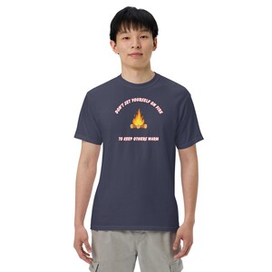 May include: A navy blue t-shirt with a pink graphic that says "Don't set yourself on fire to keep others warm". The graphic also includes a cartoon image of a campfire.