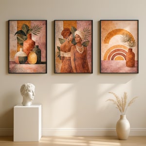 May include: Three framed art prints with black borders. The prints feature watercolor illustrations. One print shows vases with foliage, another depicts two women, and the third displays a rainbow and vase. The color palette includes earth tones.