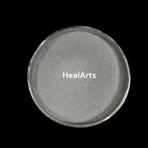 Op de afbeelding: Een rond, zilverkleurig object met een textuur. De tekst "HealArts" is in het wit over het midden van het object gedrukt. Het object staat tegen een zwarte achtergrond.
